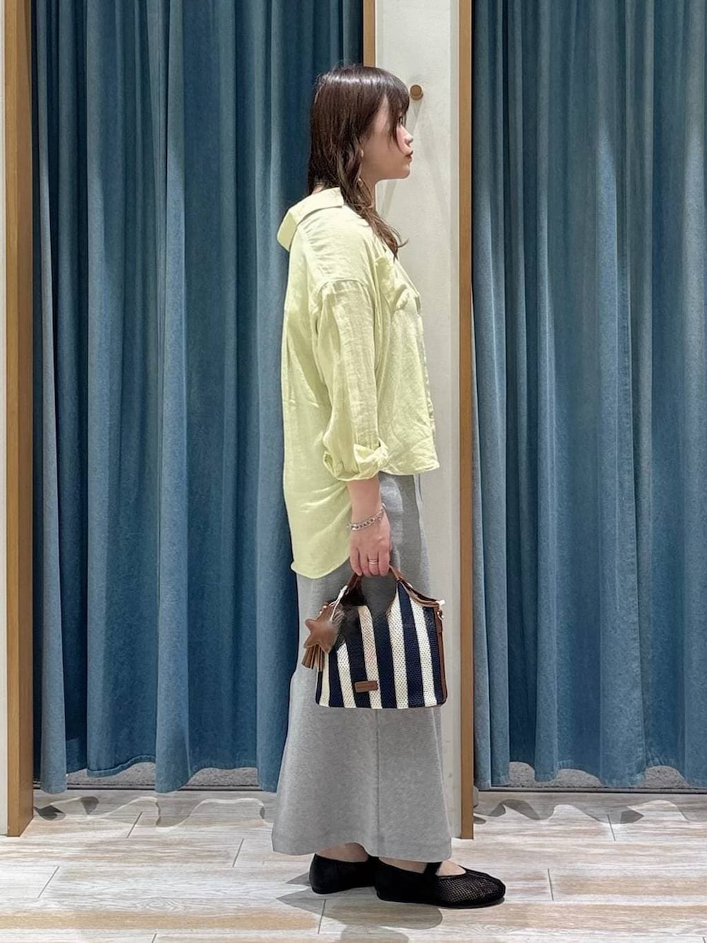 イエロー系のシャツ/ブラウス、ブラック系のパンプス、ブルー系のショルダーバッグを着用したレディースの春コーディネートの2枚目の写真