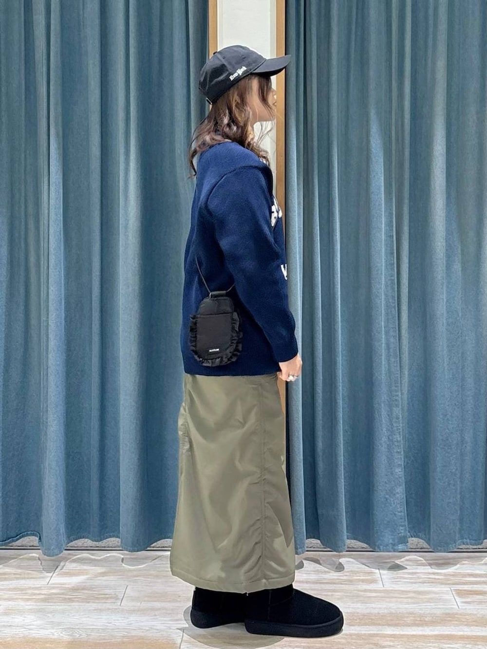 グリーン系のスカート、ブラック系のブーツ、ブルー系のニット/セーターを着用したレディースの秋コーディネートの2枚目の写真