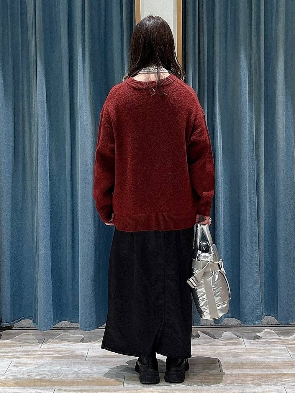 シルバー系のトートバッグ、ブラック系のブーツ、レッド系のニット/セーターを着用したレディースの冬コーディネートの3枚目の写真