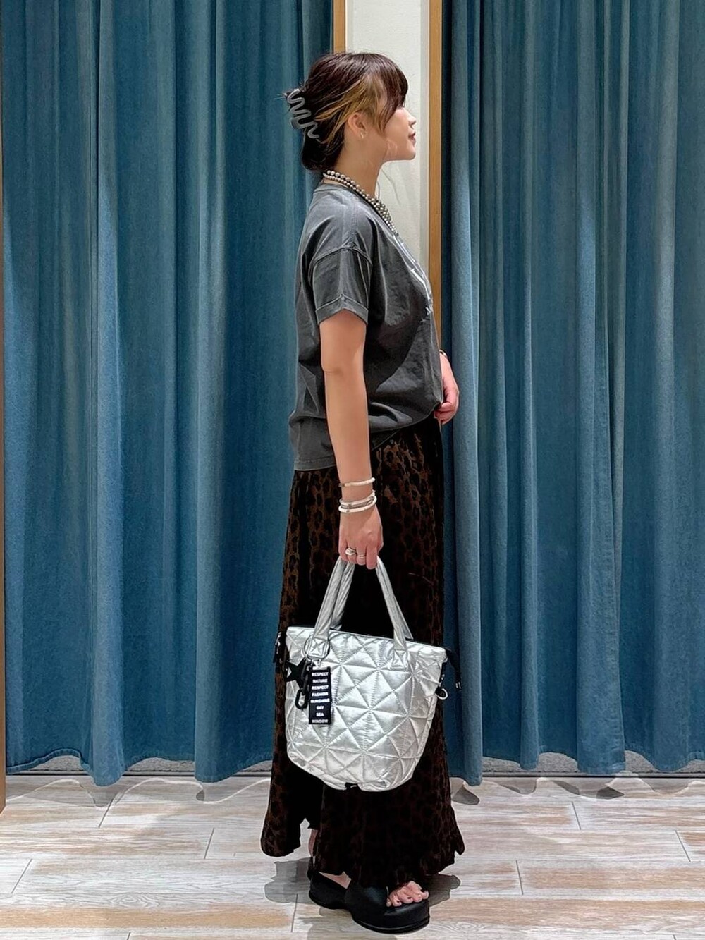 グレー系のTシャツ/カットソー、ブラウン系のスカート、シルバー系のトートバッグを着用したレディースの夏コーディネートの2枚目の写真