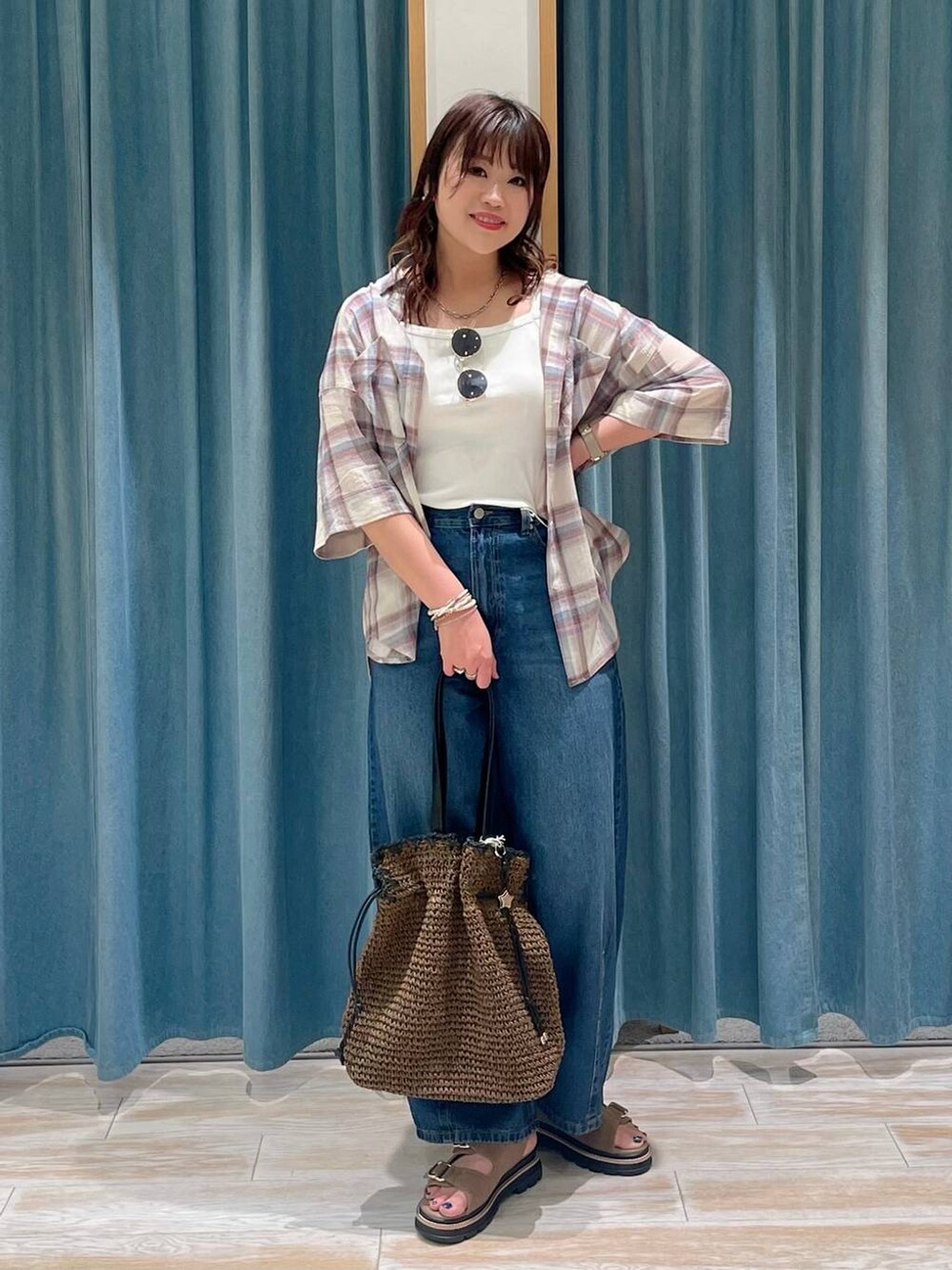 ホワイト系のキャミソール、ベージュ系のサンダル、ブルー系のデニムパンツを着用したレディースの春コーディネートの4枚目の写真