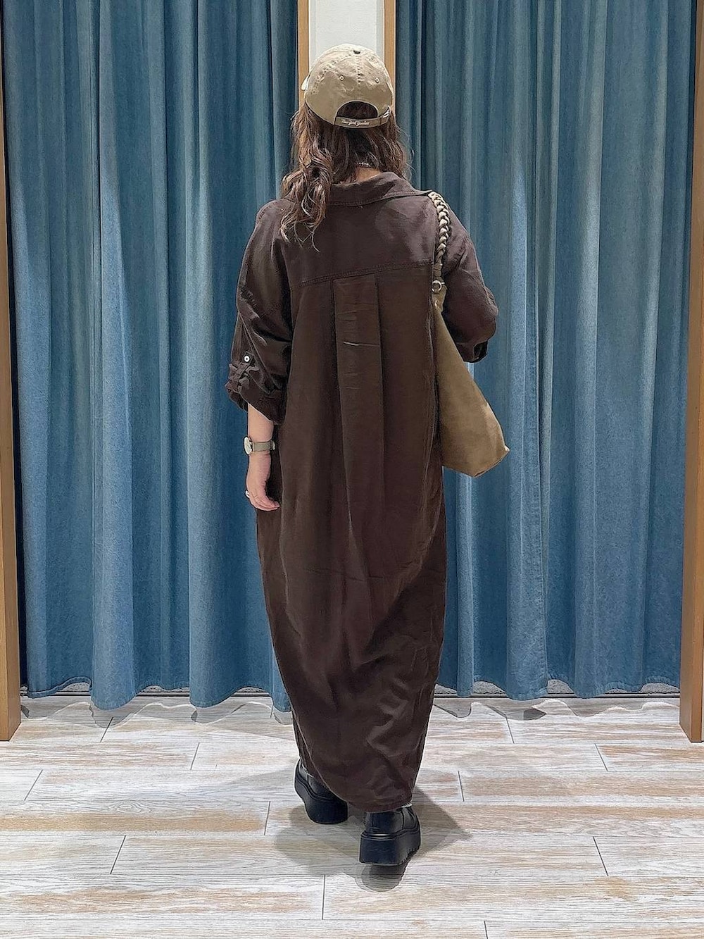 ブラウン系のワンピース、ブルー系のデニムパンツ、ブラック系のブーツを着用したレディースの秋コーディネートの3枚目の写真