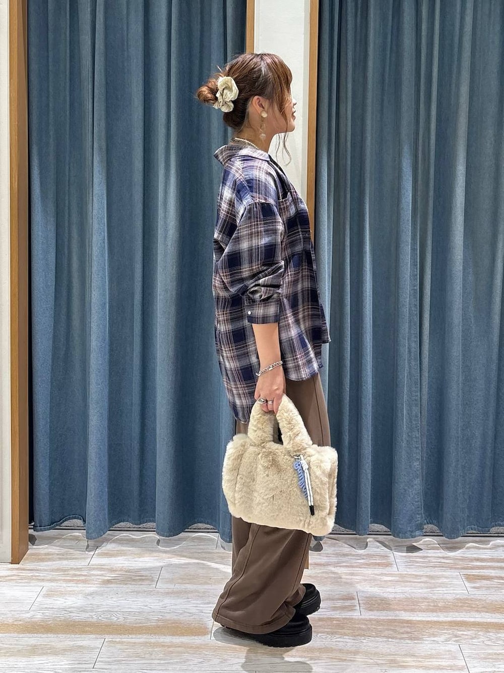 ベージュ系のトートバッグ、ブラウン系のスウェットパンツ、ブラック系のブーツを着用したレディースの秋コーディネートの2枚目の写真