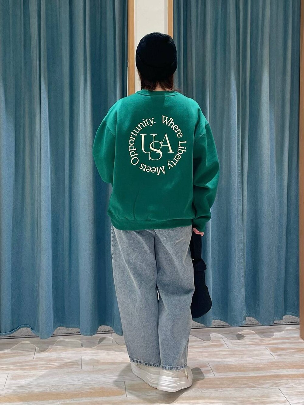 ホワイト系のスニーカー、ブルー系のデニムパンツ、ブラック系のハンドバッグを着用したレディースの冬コーディネートの3枚目の写真