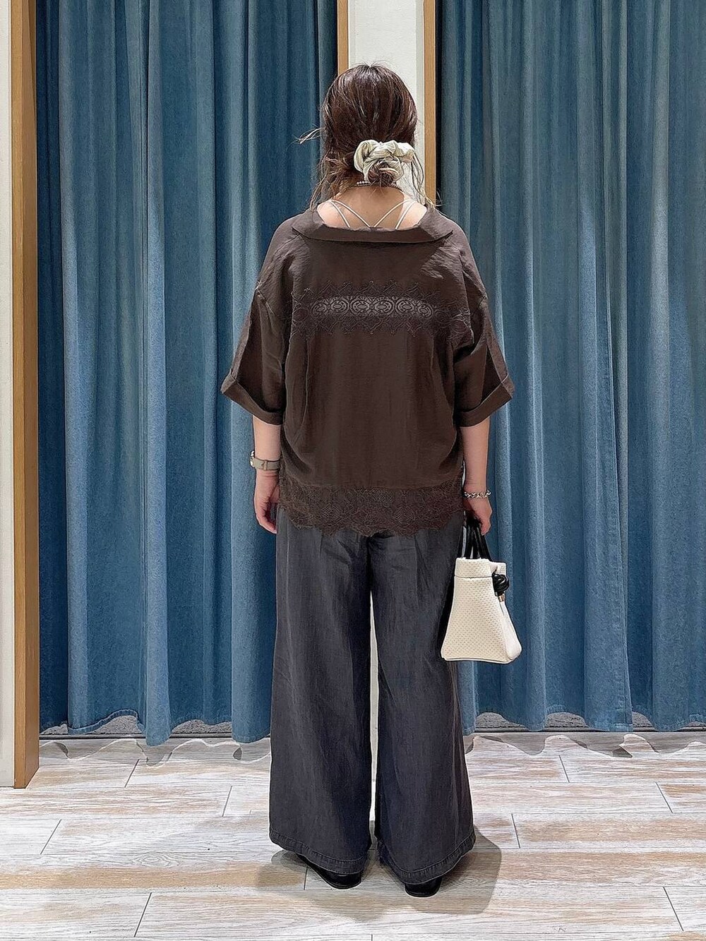 ブラック系のデニムパンツ、ブラック系のサンダル、ベージュ系のショルダーバッグを着用したレディースの夏コーディネートの3枚目の写真