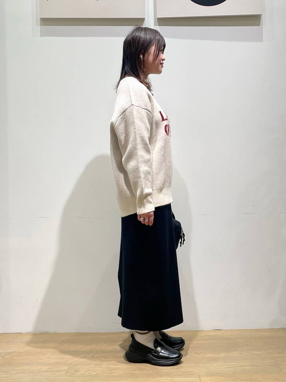 ブラック系のローファー、ブラック系のハンドバッグ、ホワイト系のニット/セーターを着用したレディースの秋コーディネートの2枚目の写真