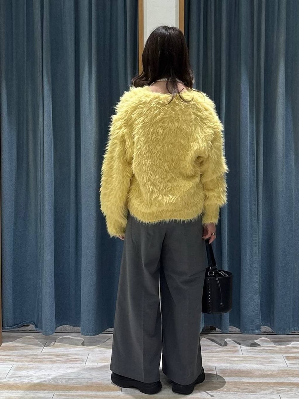 グレー系のその他パンツ、イエロー系のカーディガン/ボレロ、ブラック系のハンドバッグを着用したレディースの冬コーディネートの3枚目の写真