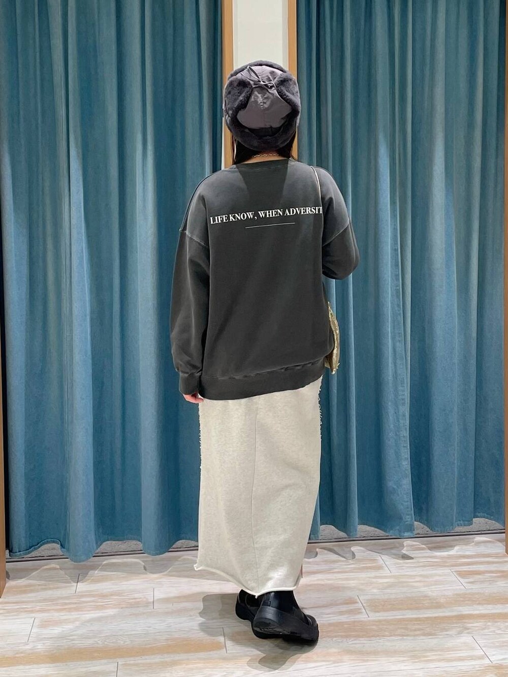 ブラック系のブーツ、グレー系のスウェット、ゴールド系のショルダーバッグを着用したレディースの冬コーディネートの3枚目の写真