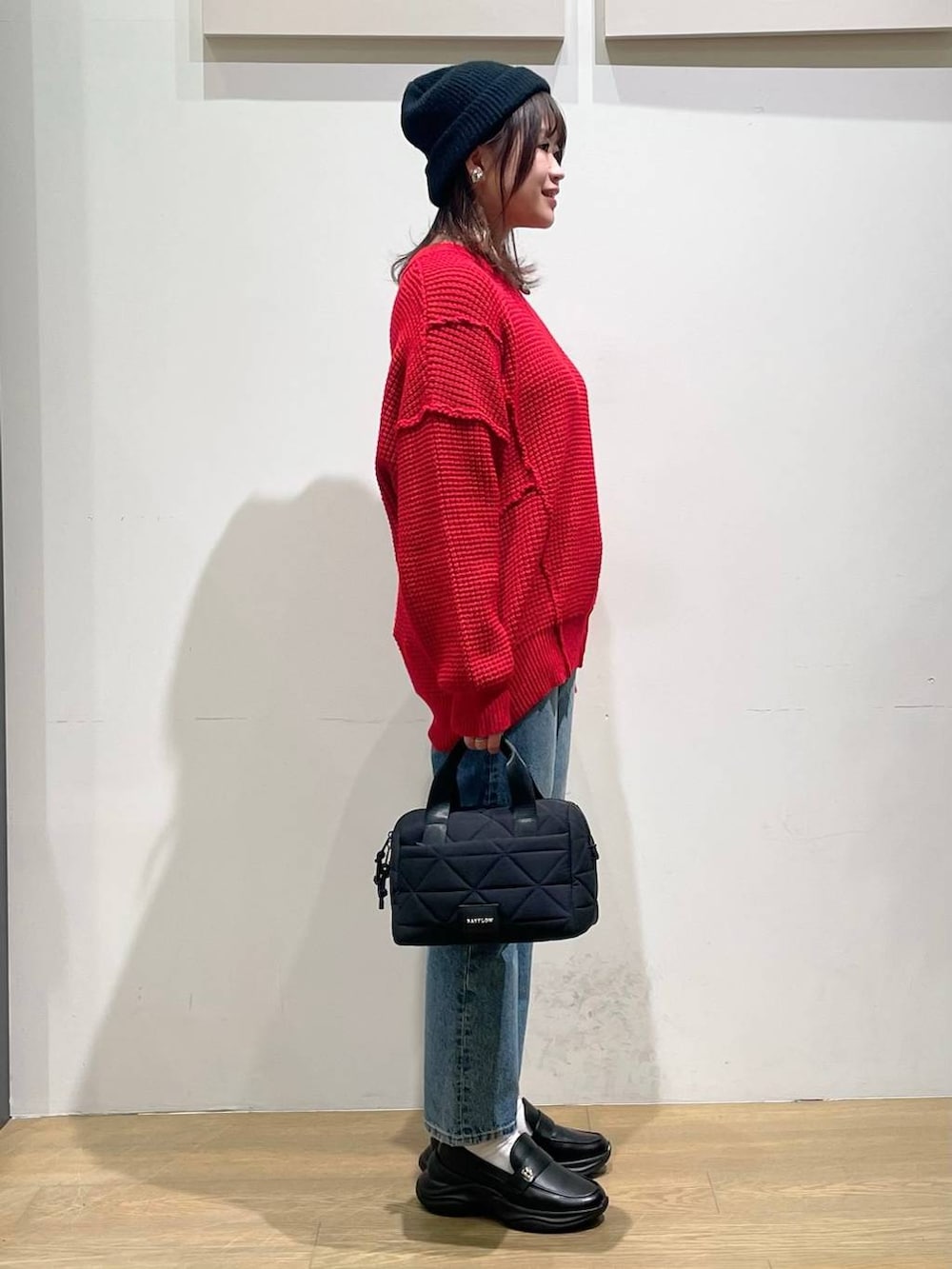 ブラック系のローファー、ブラック系のハンドバッグ、レッド系のニット/セーターを着用したレディースの秋コーディネートの2枚目の写真