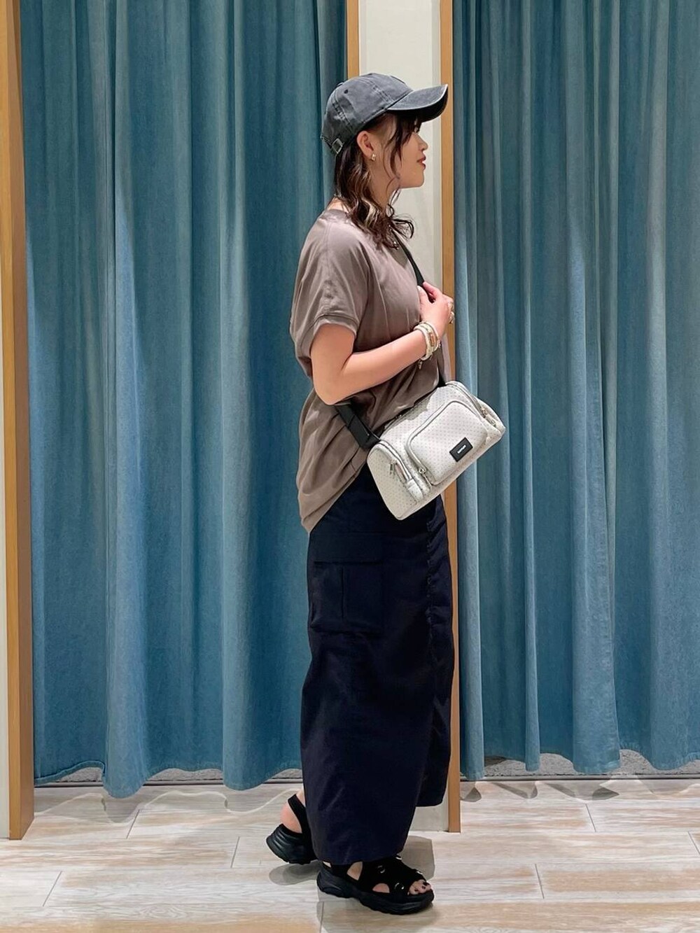 ブラウン系のTシャツ/カットソー、ブラック系のスカート、ブラック系のサンダルを着用したレディースの春コーディネートの2枚目の写真