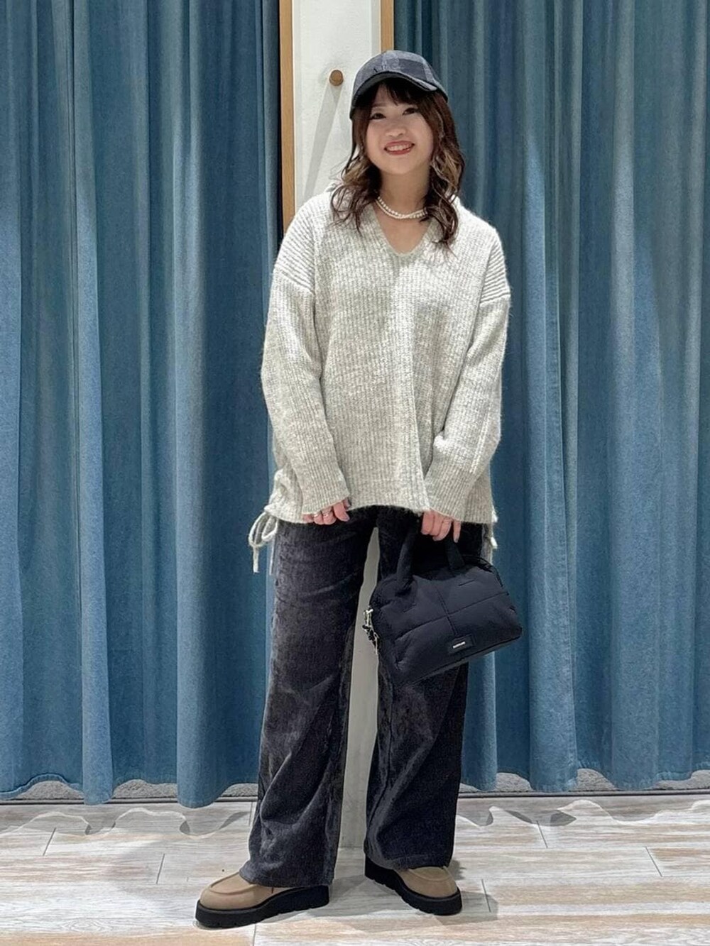 ブラック系のボストンバッグ、ベージュ系のブーツ、グレー系のその他パンツを着用したレディースの秋コーディネートの4枚目の写真