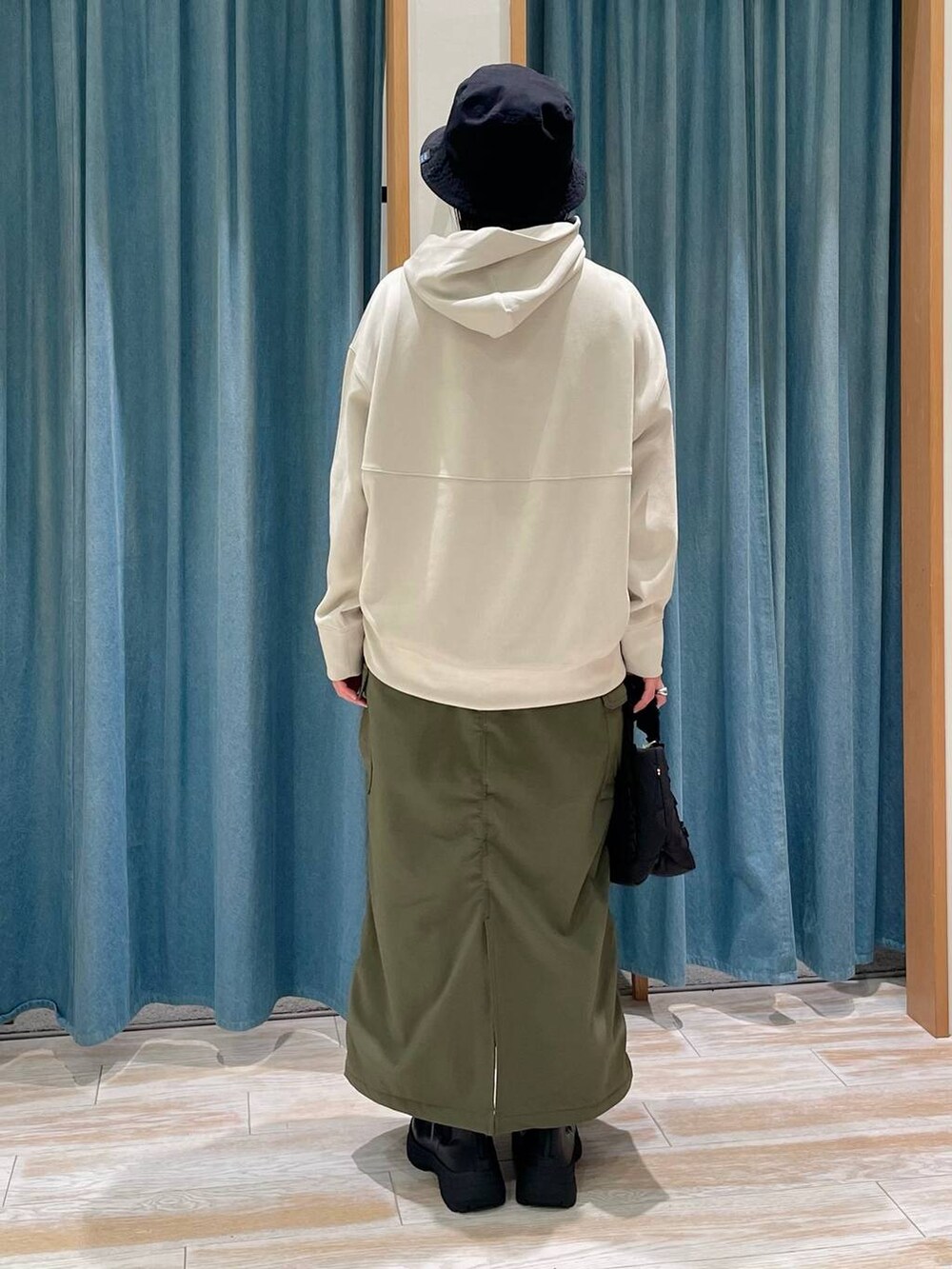 ホワイト系のパーカー、グリーン系のスカート、ブラック系のブーツを着用したレディースの秋コーディネートの3枚目の写真