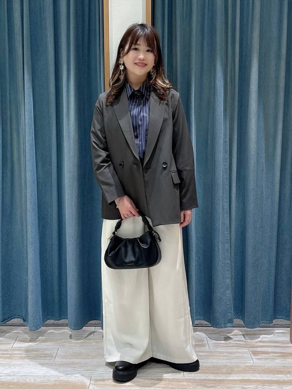 ブラック系のブーツ、ブラック系のハンドバッグ、グレー系のテーラードジャケットを着用したレディースの春コーディネートの4枚目の写真