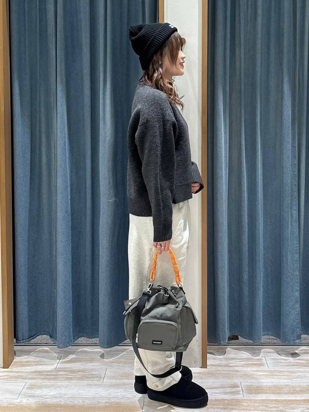 ブラック系のブーツ、グリーン系のハンドバッグ、グレー系のニット/セーターを着用したレディースの冬コーディネートの2枚目の写真