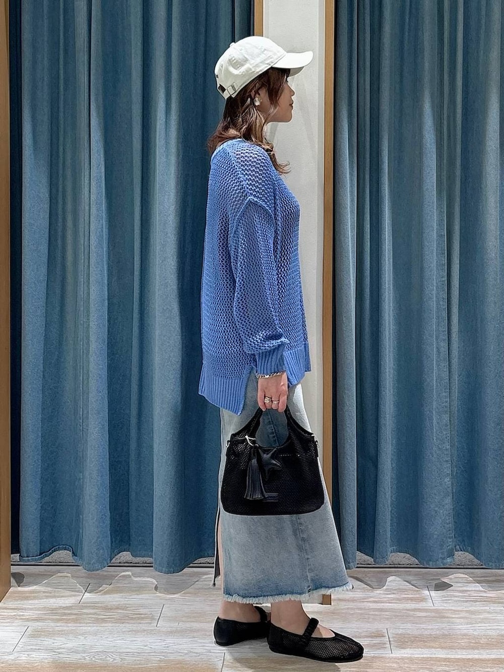 ブルー系のデニムスカート、ブラック系のショルダーバッグ、ブラック系のパンプスを着用したレディースの春コーディネートの2枚目の写真