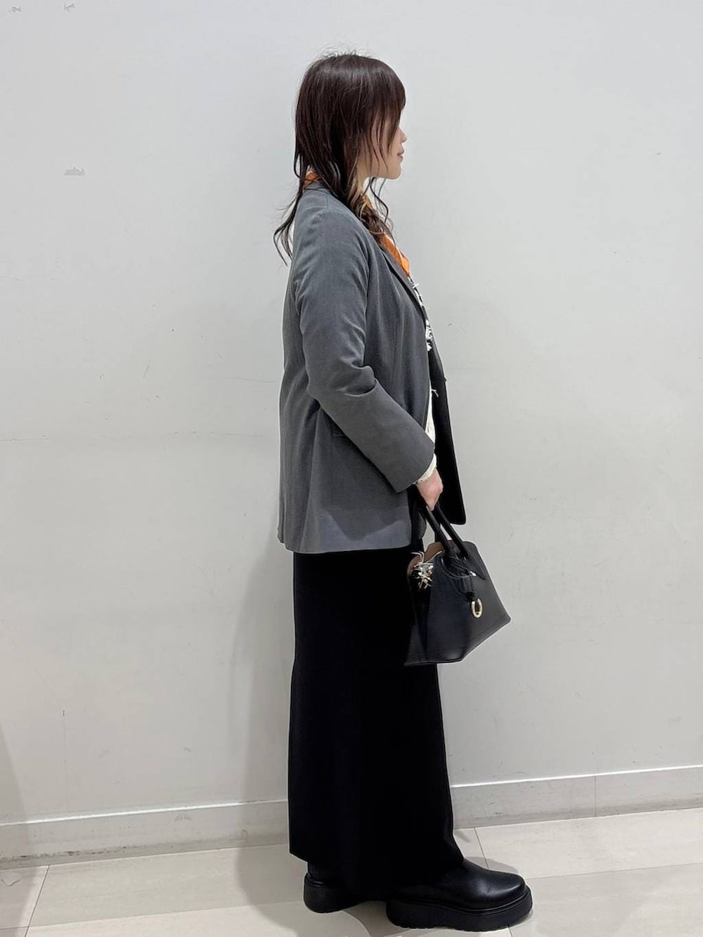 ブラック系のショルダーバッグ、ブラック系のブーツ、グレー系のテーラードジャケットを着用したレディースの冬コーディネートの2枚目の写真