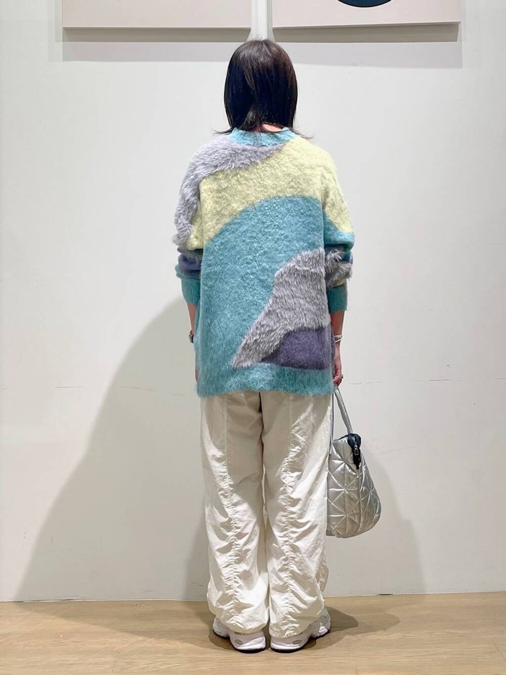 ベージュ系のその他パンツ、ブルー系のカーディガン/ボレロ、シルバー系のトートバッグを着用したレディースの秋コーディネートの2枚目の写真