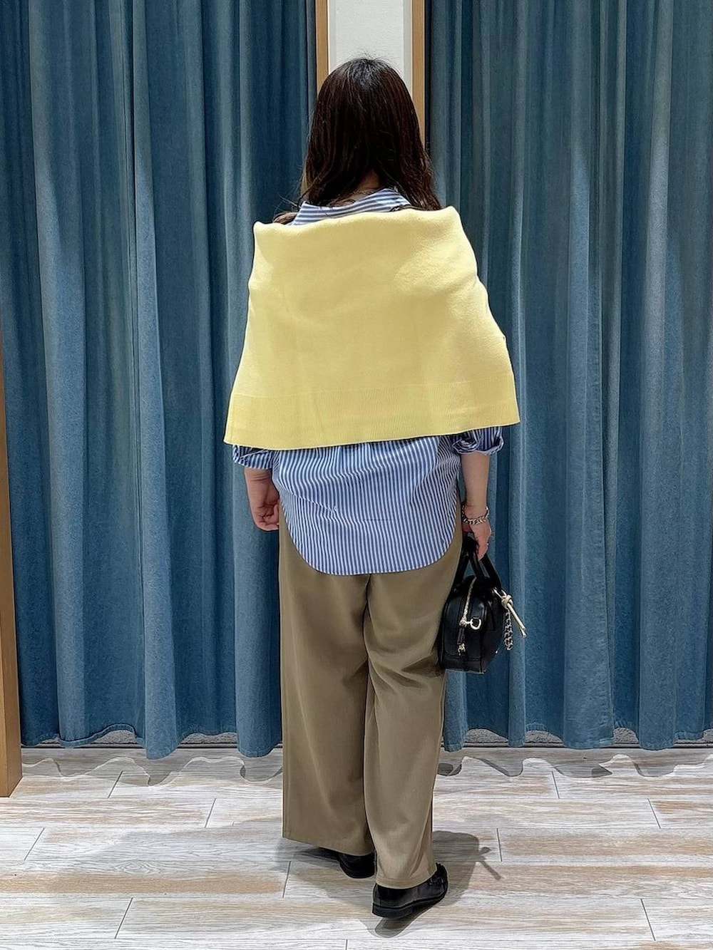 ブラック系のローファー、ブラック系のハンドバッグ、イエロー系のニット/セーターを着用したレディースの春コーディネートの3枚目の写真