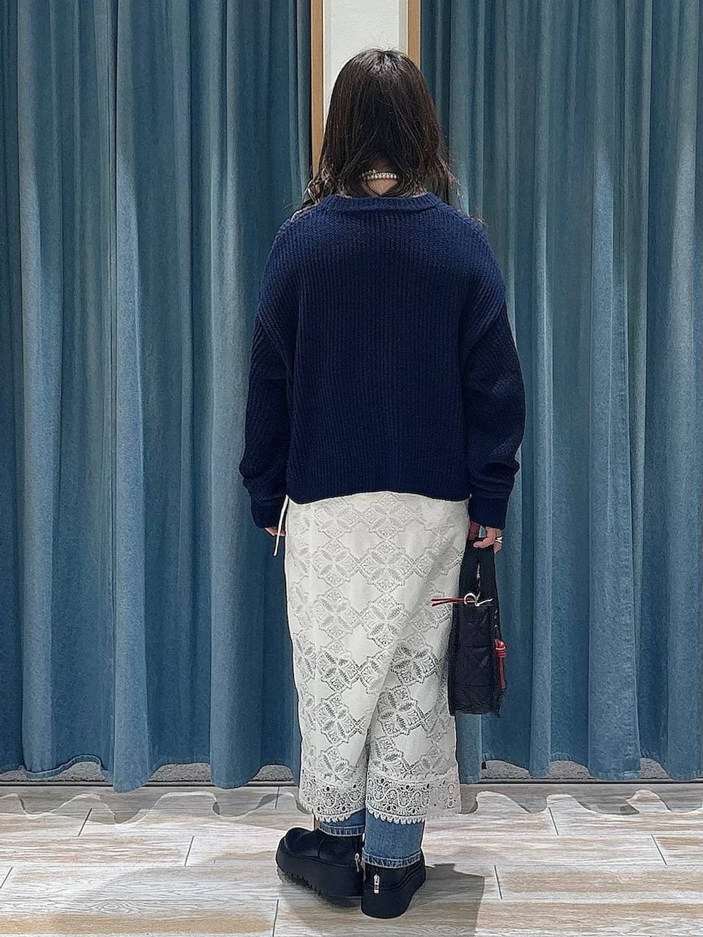 ブラック系のショルダーバッグ、ブラック系のブーツ、ブルー系のニット/セーターを着用したレディースの冬コーディネートの3枚目の写真