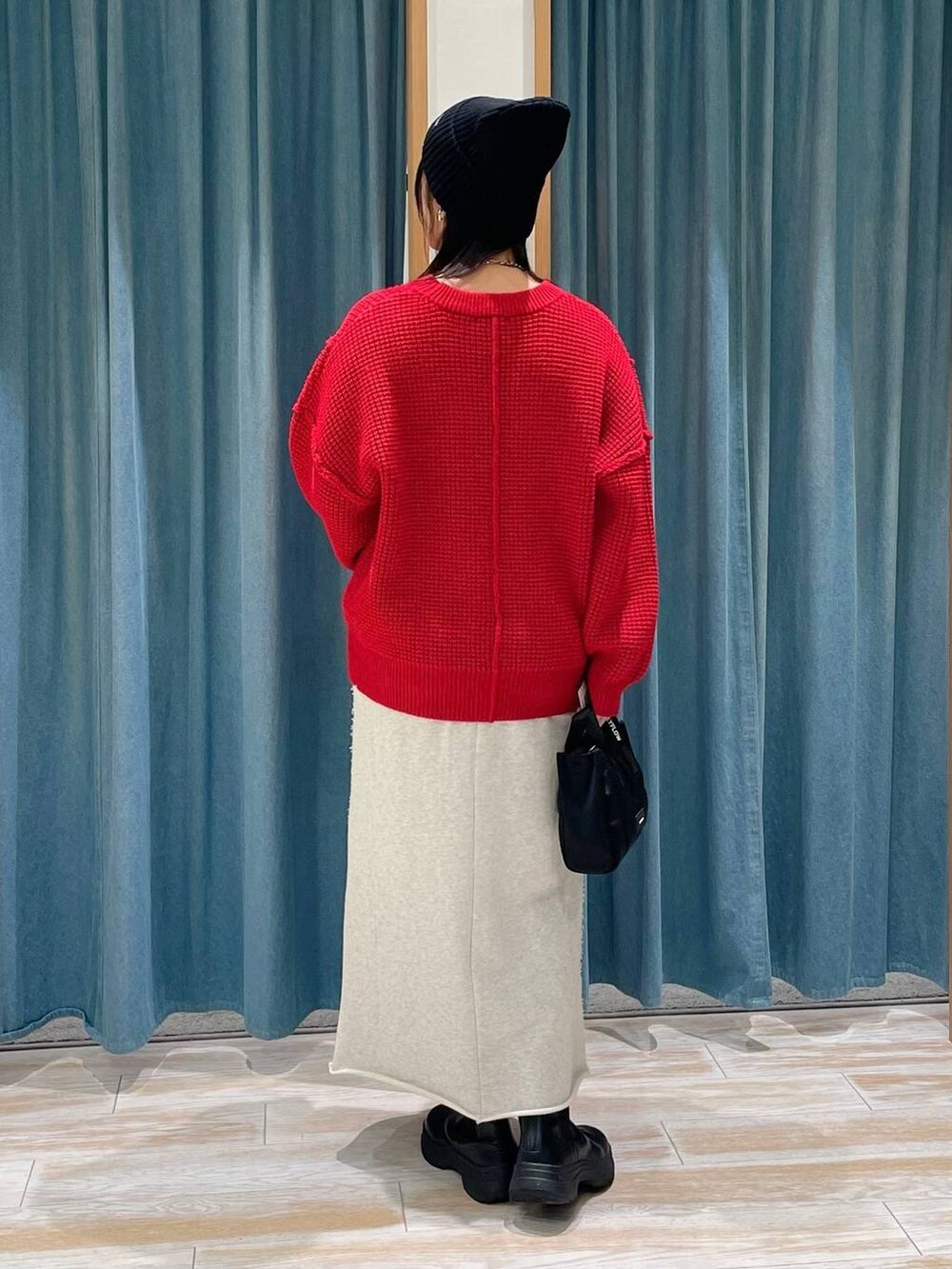 ブラック系のブーツ、レッド系のニット/セーター、ブラック系のショルダーバッグを着用したレディースの冬コーディネートの3枚目の写真