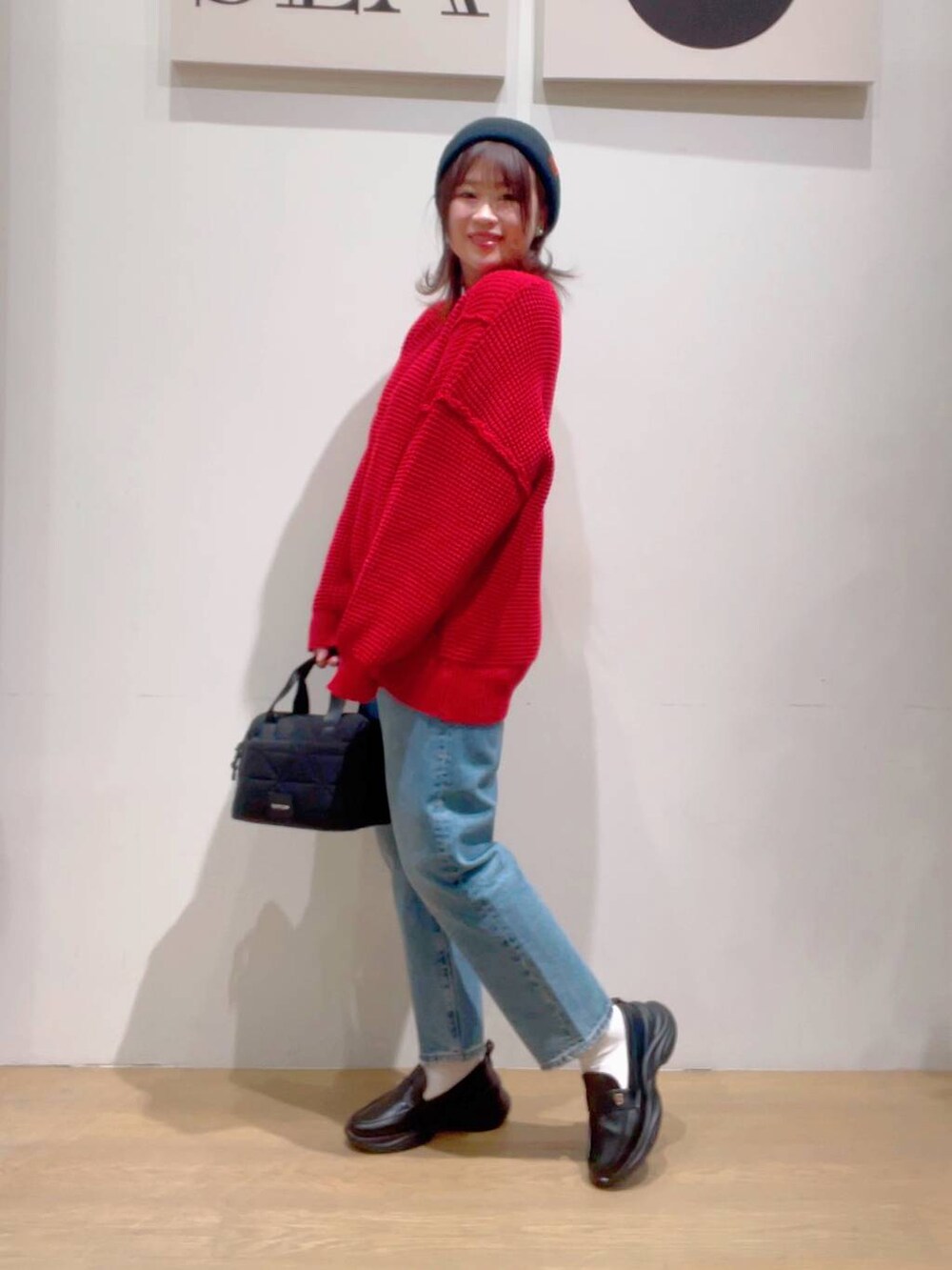 ブラック系のローファー、ブラック系のハンドバッグ、レッド系のニット/セーターを着用したレディースの秋コーディネートの3枚目の写真