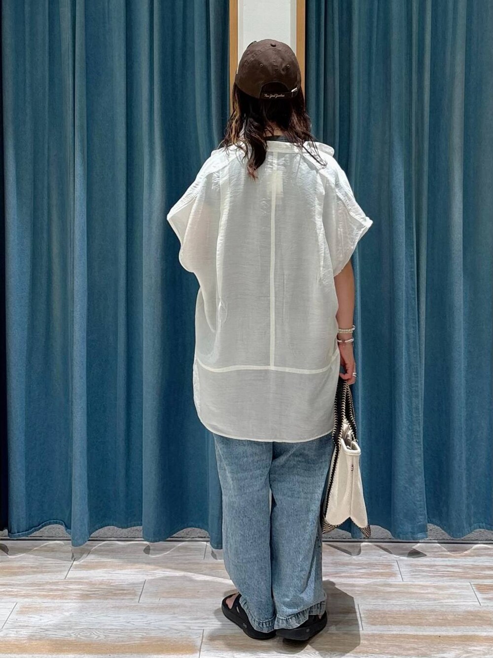 ホワイト系のシャツ/ブラウス、ベージュ系のトートバッグ、ブルー系のデニムパンツを着用したレディースの夏コーディネートの3枚目の写真