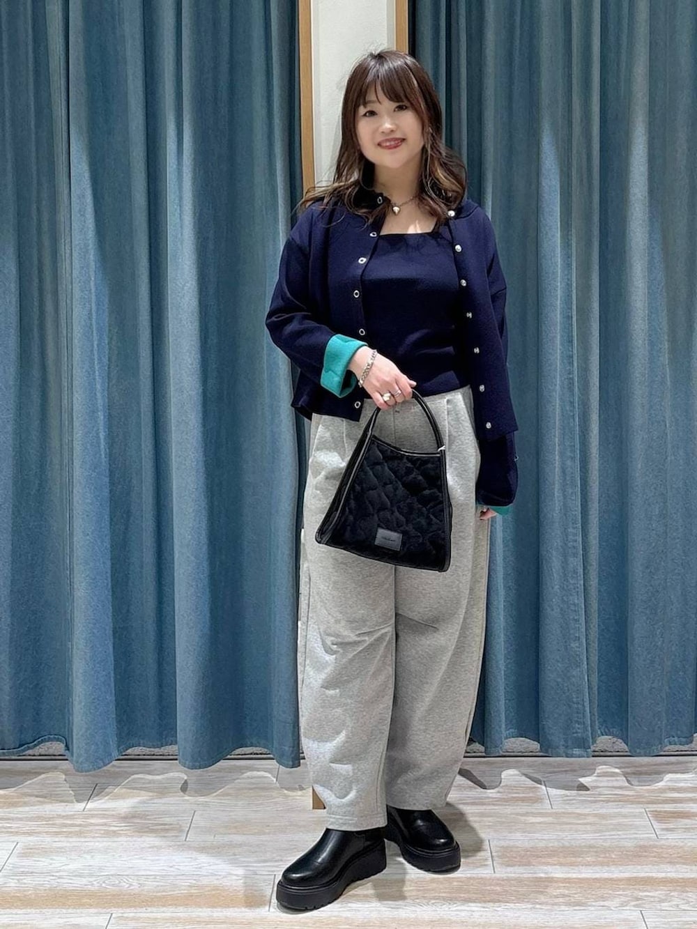 ブラック系のブーツ、ブラック系のハンドバッグ、ブルー系のカーディガン/ボレロを着用したレディースの冬コーディネートの4枚目の写真