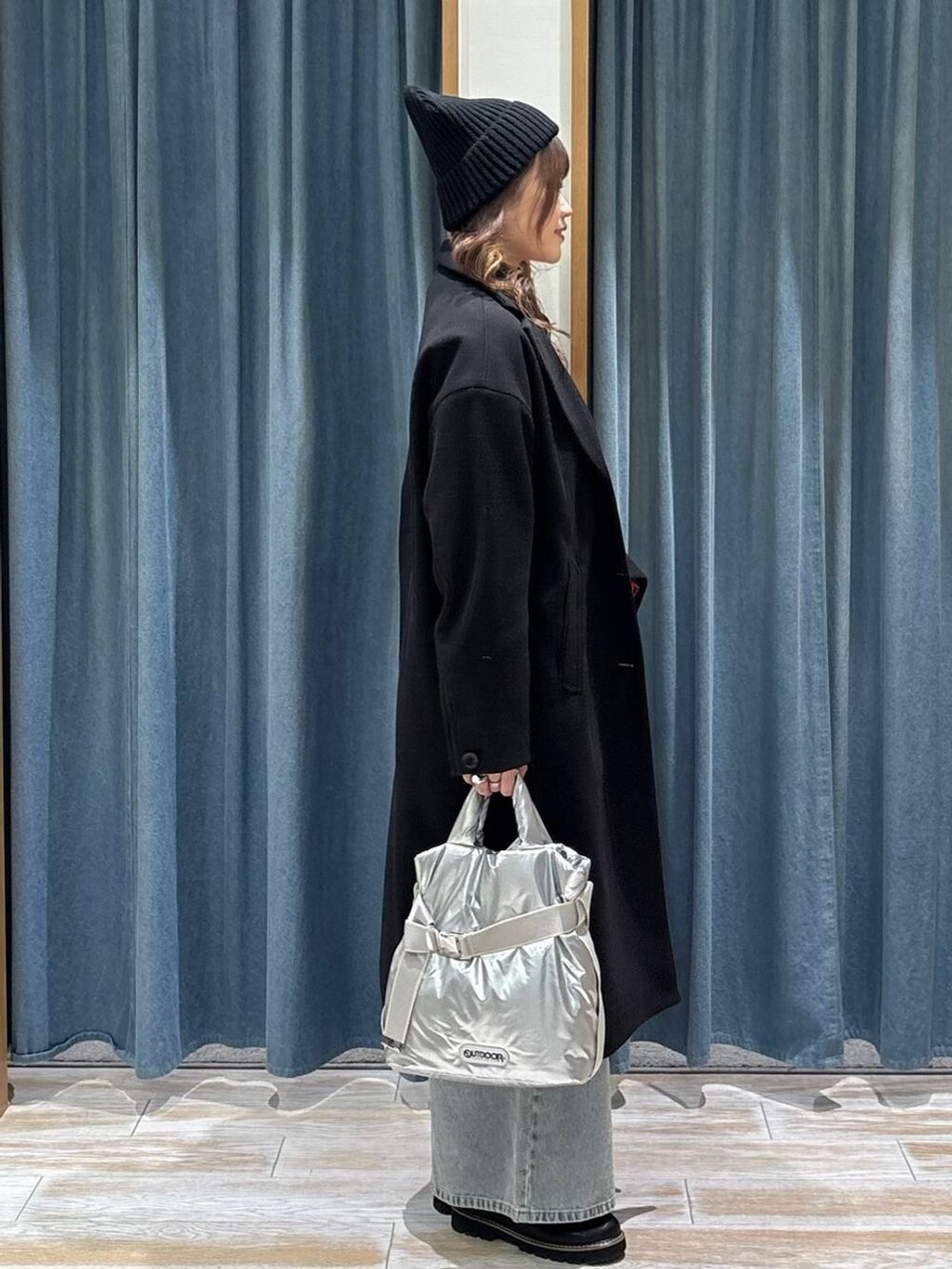 シルバー系のトートバッグ、ブラック系のチェスターコート、ブラック系のローファーを着用したレディースの秋コーディネートの2枚目の写真