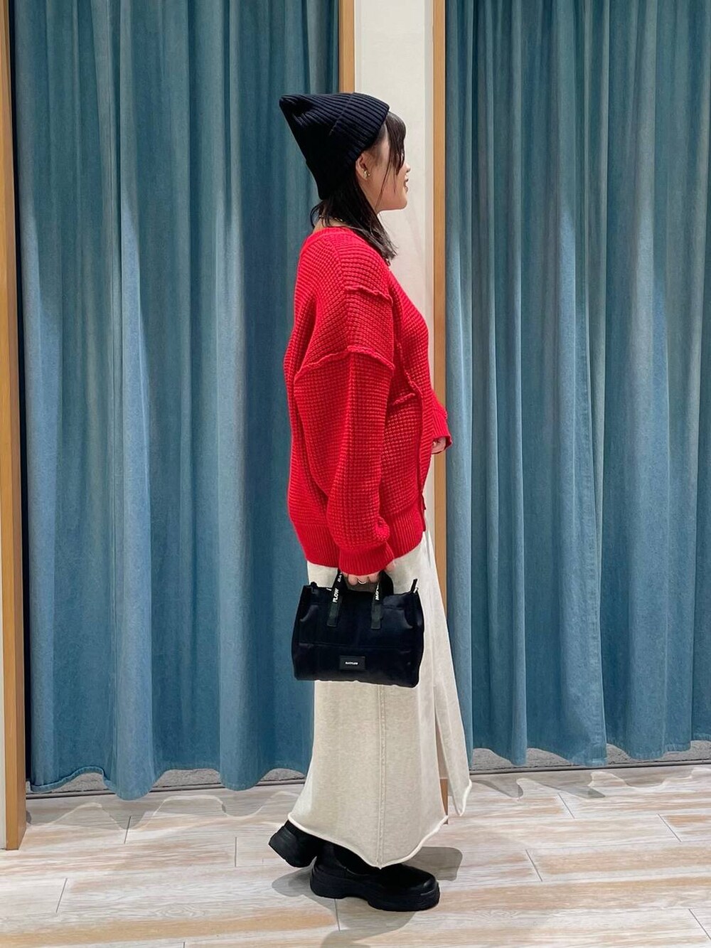 ブラック系のブーツ、レッド系のニット/セーター、ブラック系のショルダーバッグを着用したレディースの冬コーディネートの2枚目の写真
