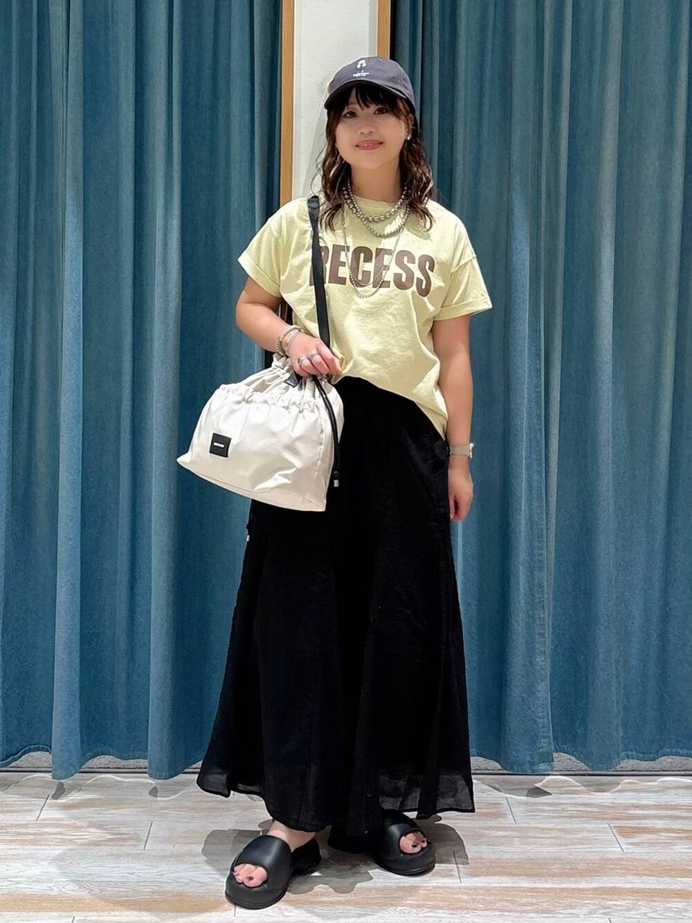 ホワイト系のトートバッグ、ベージュ系のTシャツ/カットソー、ブラック系のスカートを着用したレディースの夏コーディネートの4枚目の写真