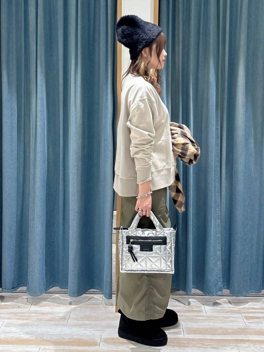 シルバー系のショルダーバッグ、グリーン系のスカート、ブラック系のブーツを着用したレディースの秋コーディネートの2枚目の写真