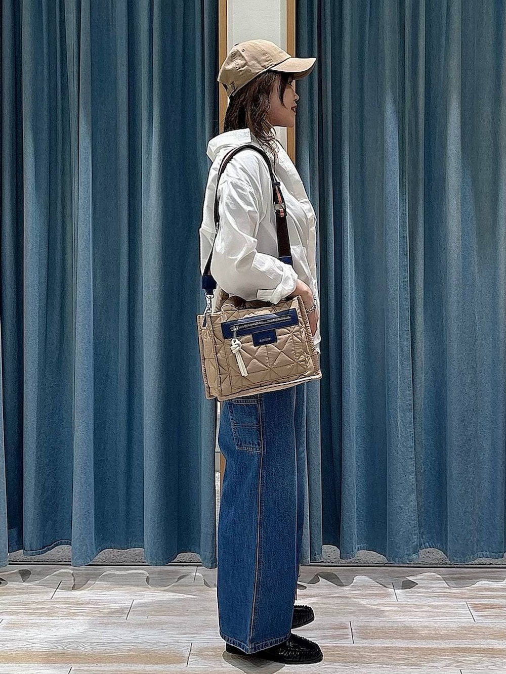 ベージュ系のショルダーバッグ、ブルー系のデニムパンツ、ブラック系のローファーを着用したレディースの春コーディネートの2枚目の写真