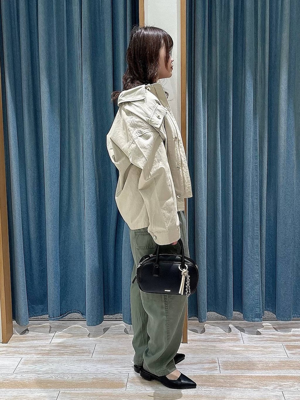 ブラック系のパンプス、ブラック系のハンドバッグ、ベージュ系のブルゾンを着用したレディースの春コーディネートの2枚目の写真