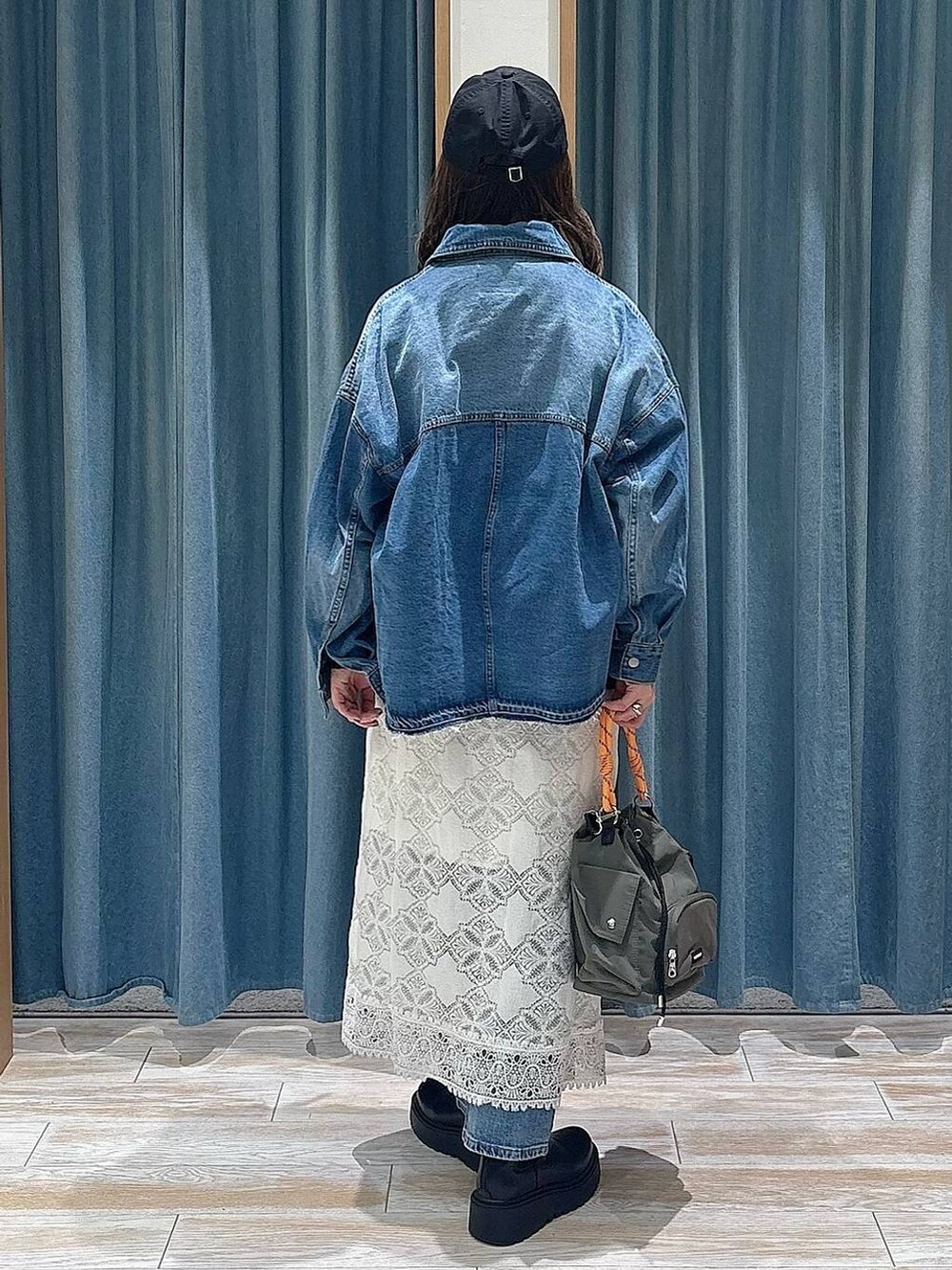 ブラック系のブーツ、ブラック系のハンドバッグ、ブルー系のデニムパンツを着用したレディースの冬コーディネートの2枚目の写真