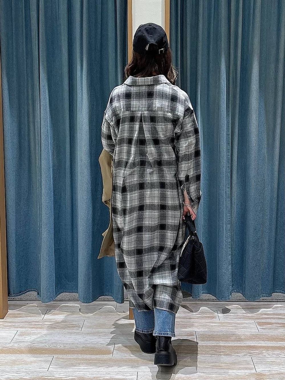 ブラック系のブーツ、ブラック系のトートバッグ、ブルー系のデニムパンツを着用したレディースの冬コーディネートの3枚目の写真