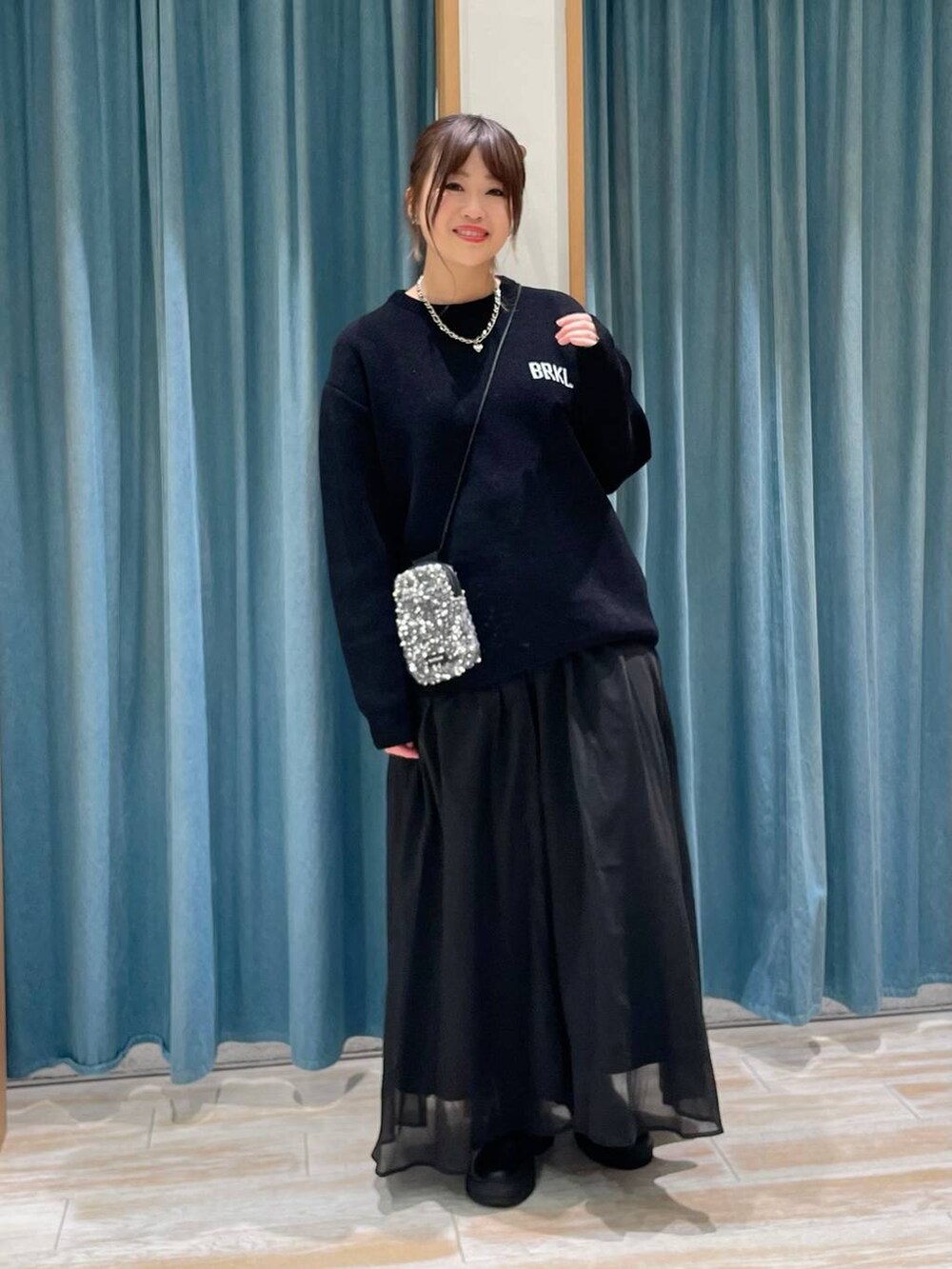 グレー系のショルダーバッグ、ブラック系のブーツ、ブラック系のニット/セーターを着用したレディースの冬コーディネートの2枚目の写真