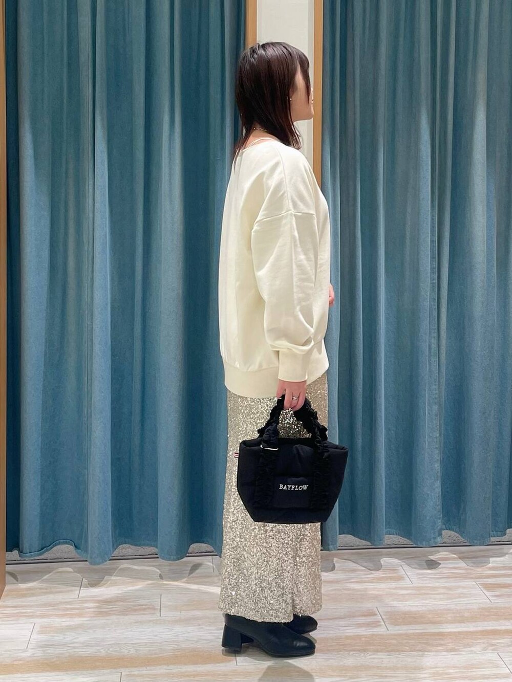 ブラック系のブーツ、ベージュ系のスカート、ブラック系のトートバッグを着用したレディースの冬コーディネートの2枚目の写真