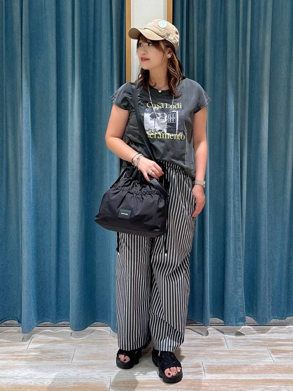 ブラック系のトートバッグ、グレー系のTシャツ/カットソー、ベージュ系のキャップを着用したレディースの夏コーディネートの3枚目の写真