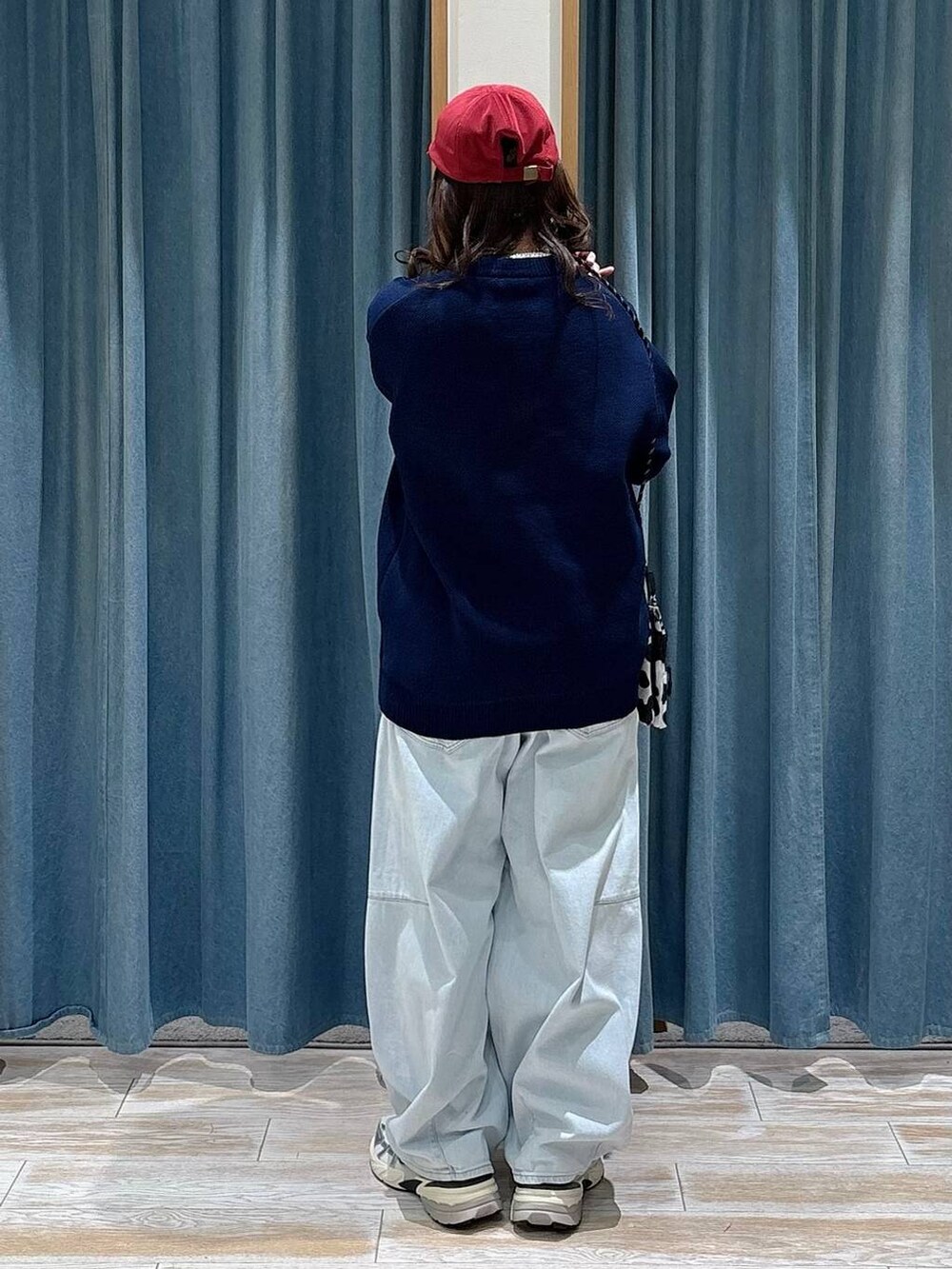 ブルー系のニット/セーター、ブルー系のデニムパンツ、レッド系のキャップを着用したレディースの冬コーディネートの3枚目の写真