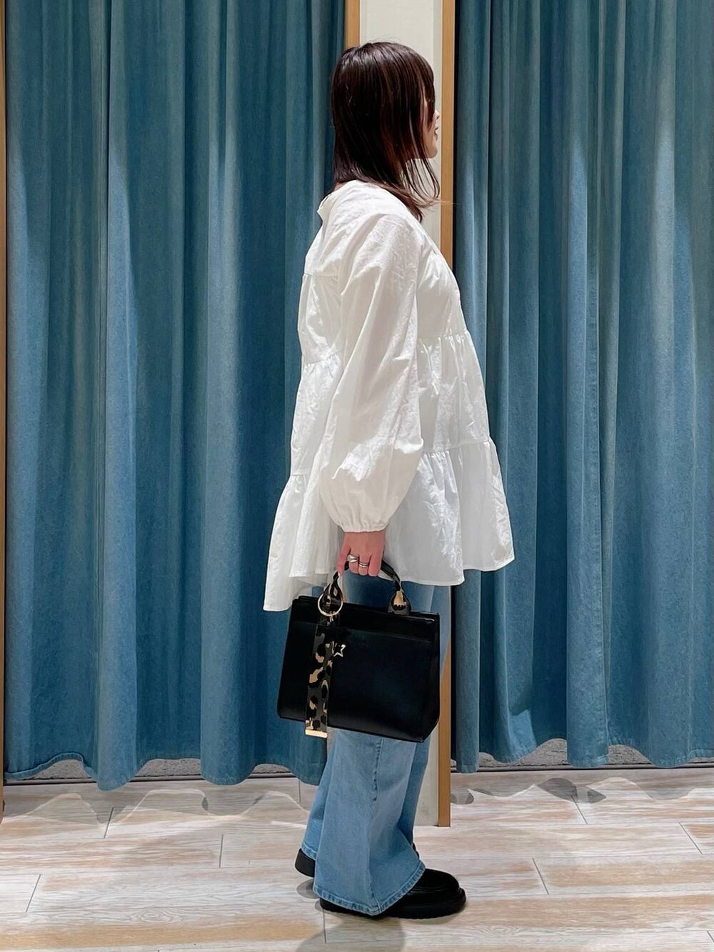 ブラック系のハンドバッグ、その他のローファー、ブルー系のデニムパンツを着用したレディースの冬コーディネートの2枚目の写真