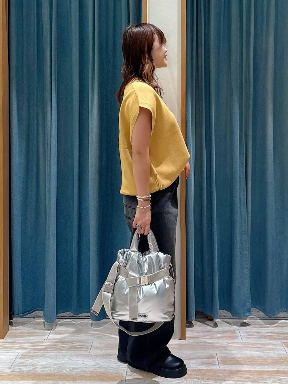 シルバー系のトートバッグ、ブラック系のサンダル、ブラック系のデニムパンツを着用したレディースの夏コーディネートの2枚目の写真