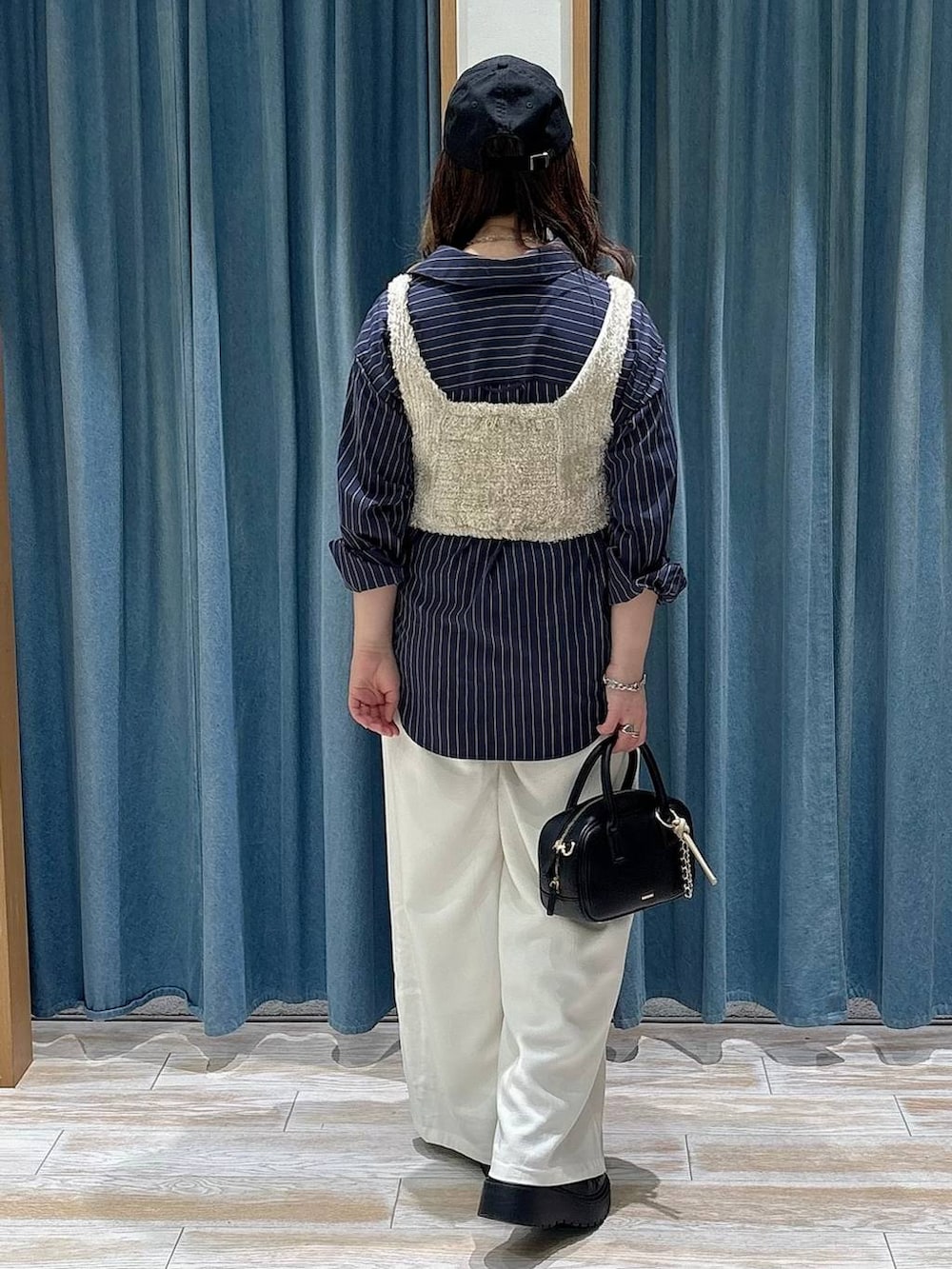 ブラック系のブーツ、ベージュ系のその他トップス、ブラック系のハンドバッグを着用したレディースの春コーディネートの3枚目の写真