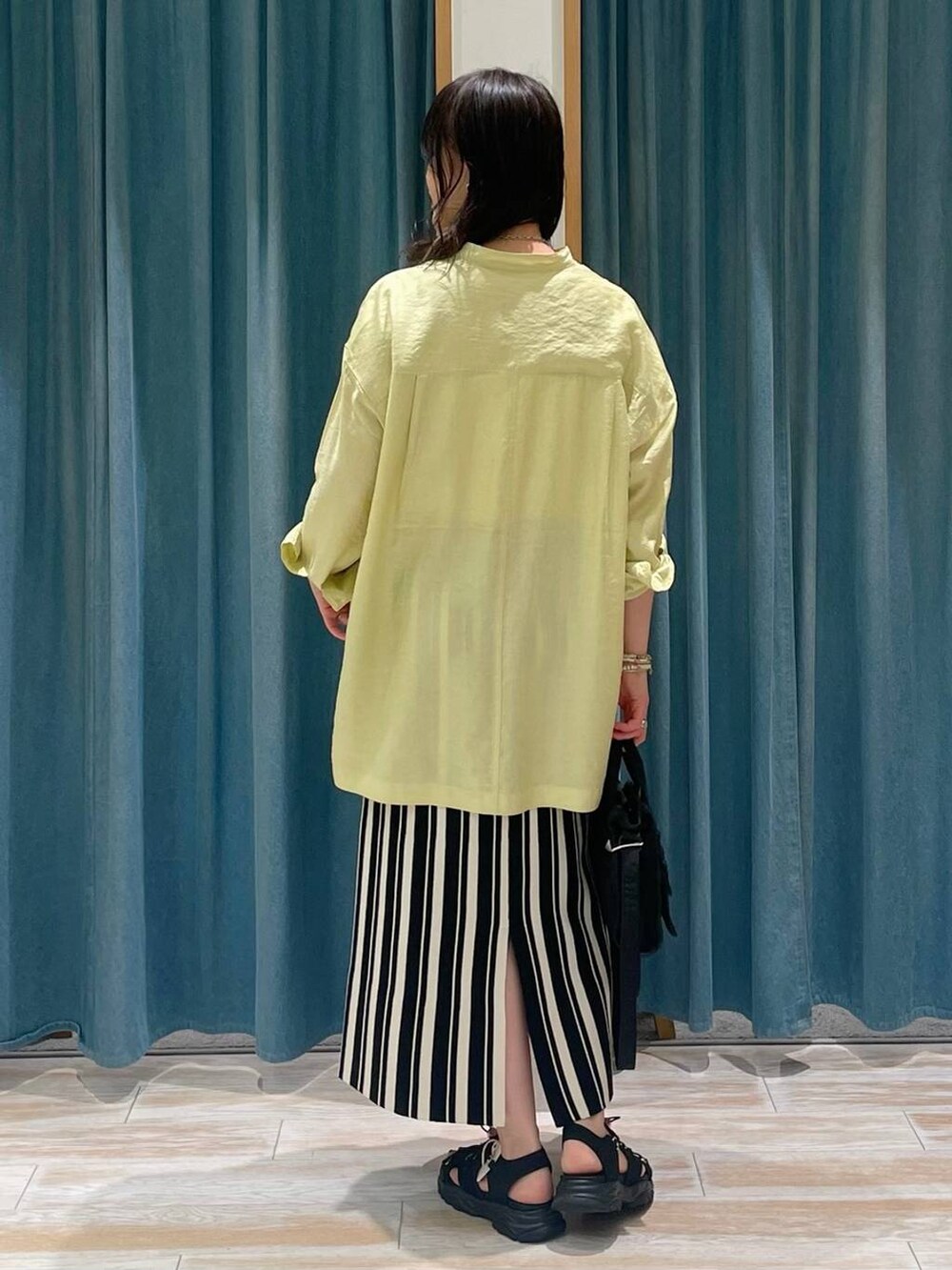 イエロー系のシャツ/ブラウス、ブラック系のショルダーバッグ、ブラック系のサンダルを着用したレディースの春コーディネートの3枚目の写真