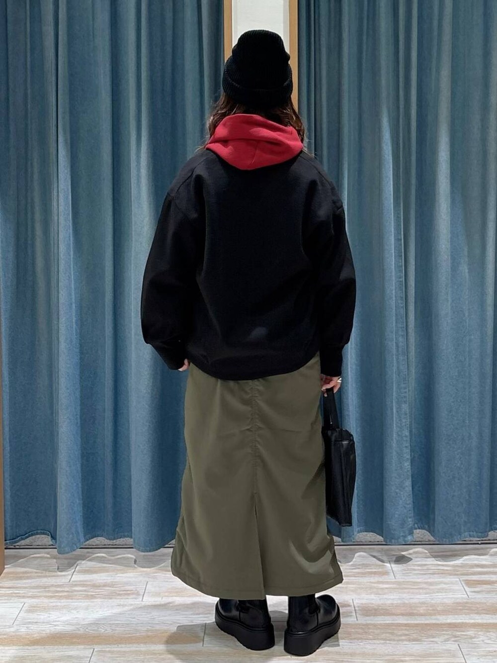 グリーン系のスカート、ブラック系のブルゾン、ブラック系のブーツを着用したレディースの秋コーディネートの2枚目の写真