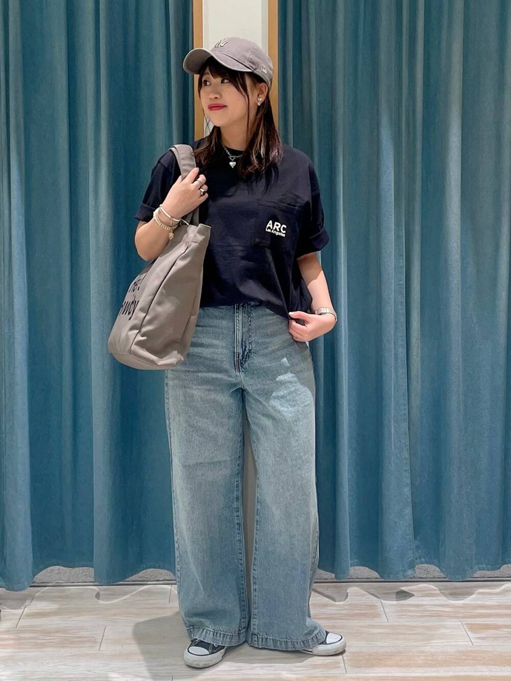 ブルー系のデニムパンツ、グリーン系のトートバッグ、ブラック系のTシャツ/カットソーを着用したレディースの春コーディネートの2枚目の写真