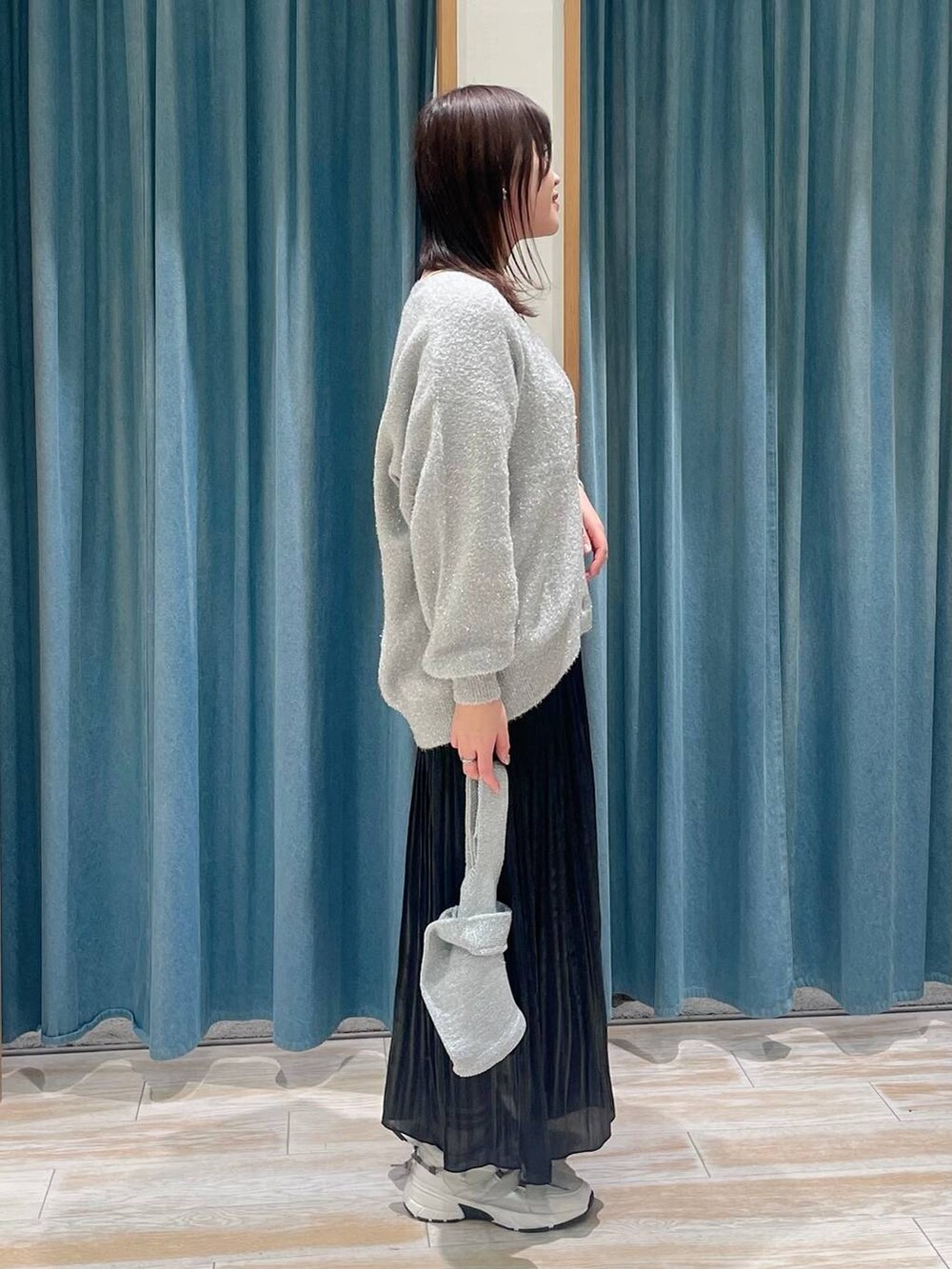 ホワイト系のスニーカー、ブラック系のスカート、グレー系のハンドバッグを着用したレディースの冬コーディネートの2枚目の写真