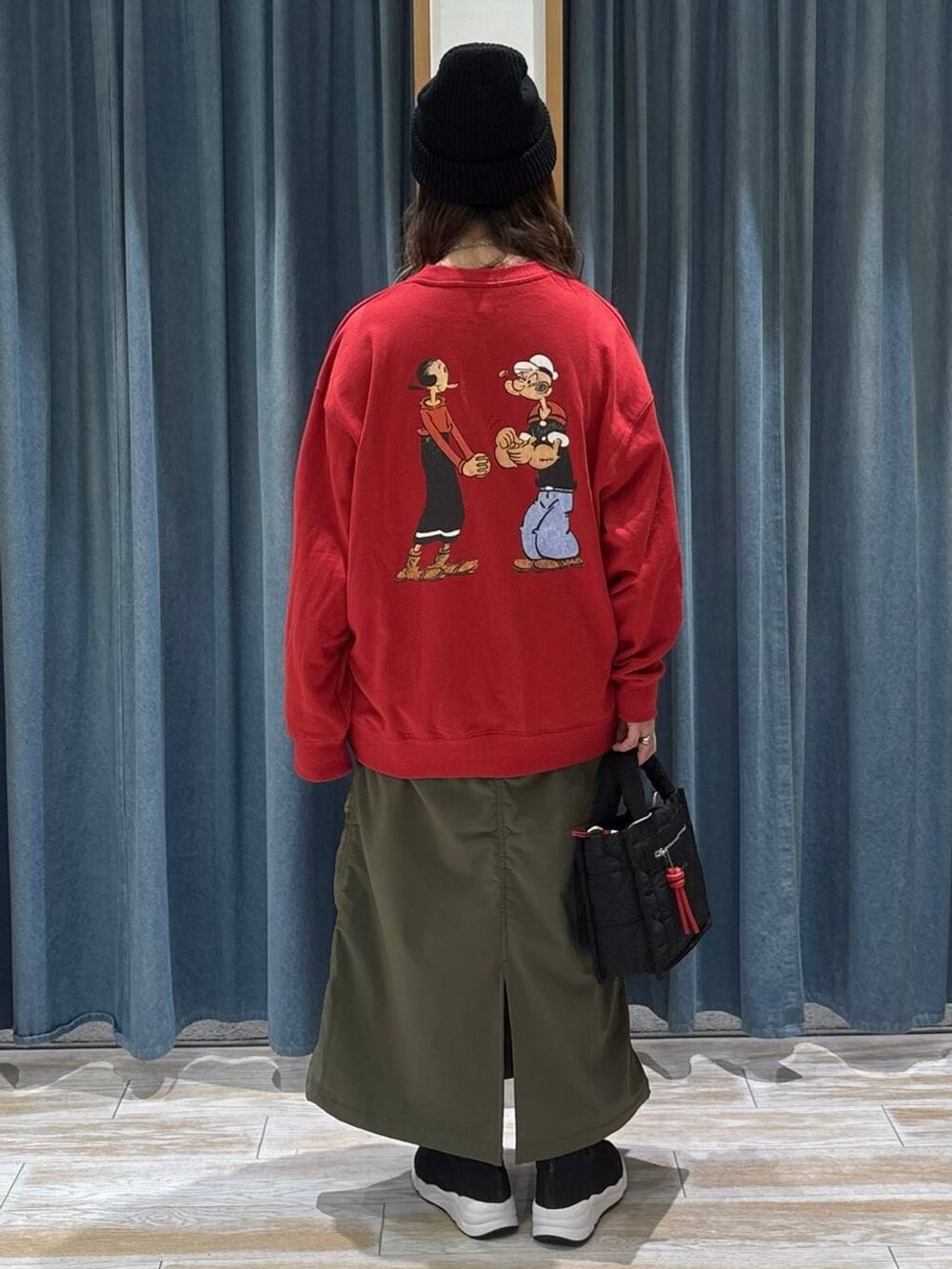 ブラック系のショルダーバッグ、グリーン系のスカート、ブラック系のブーツを着用したレディースの冬コーディネートの3枚目の写真