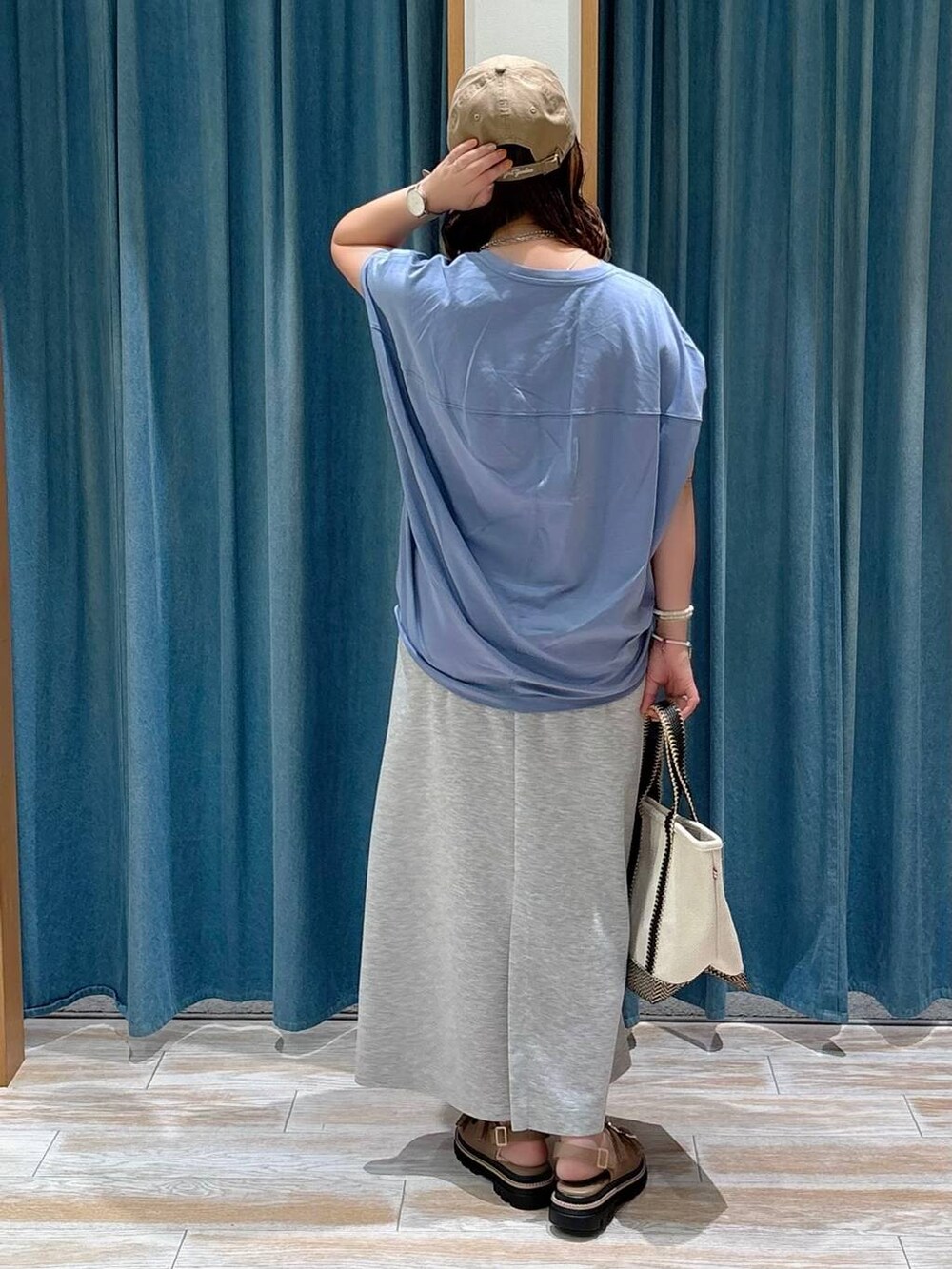 ベージュ系のトートバッグ、ブルー系のTシャツ/カットソー、ベージュ系のサンダルを着用したレディースの夏コーディネートの3枚目の写真