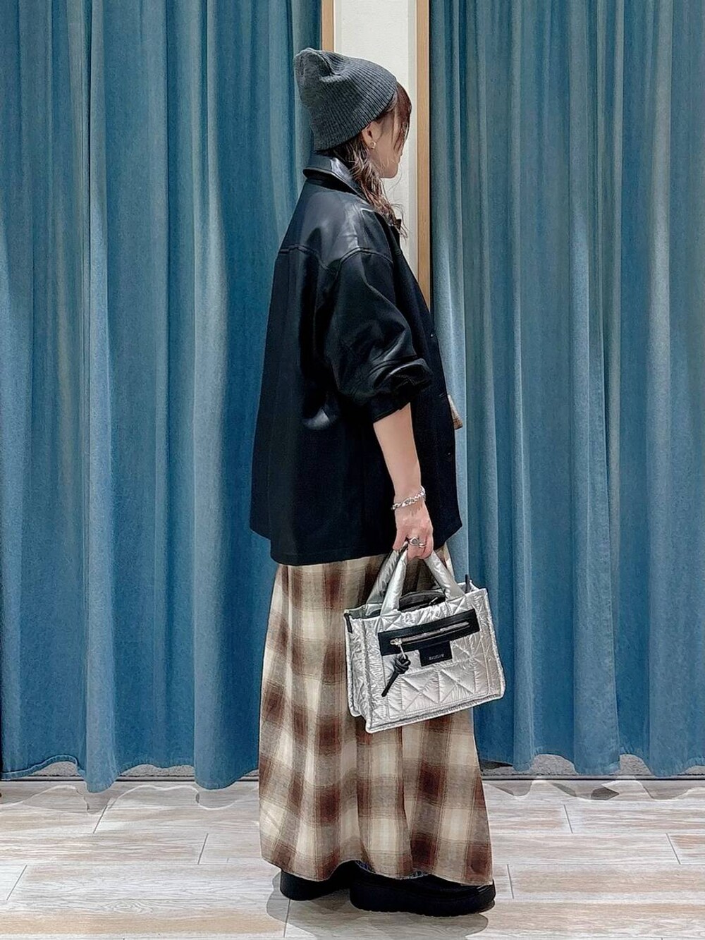 シルバー系のショルダーバッグ、ブラック系のブーツ、ブルー系のデニムパンツを着用したレディースの秋コーディネートの2枚目の写真