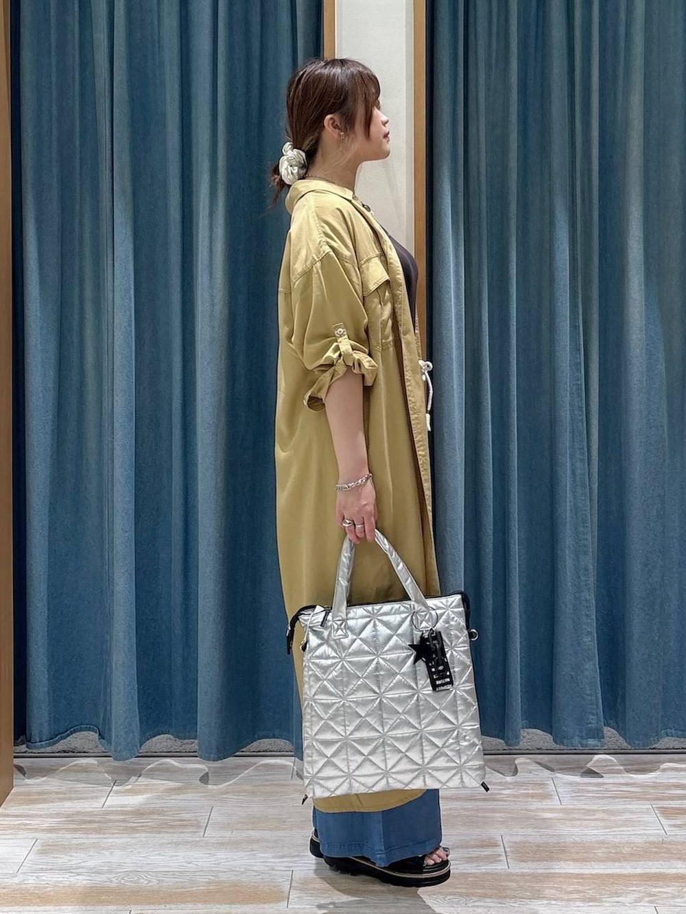 ブルー系のデニムパンツ、イエロー系のワンピース、ブラック系のサンダルを着用したレディースの春コーディネートの2枚目の写真